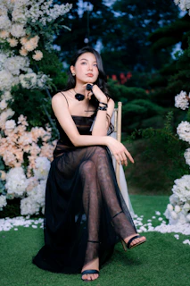 Woman in black dress sitting amidst floral decorations
