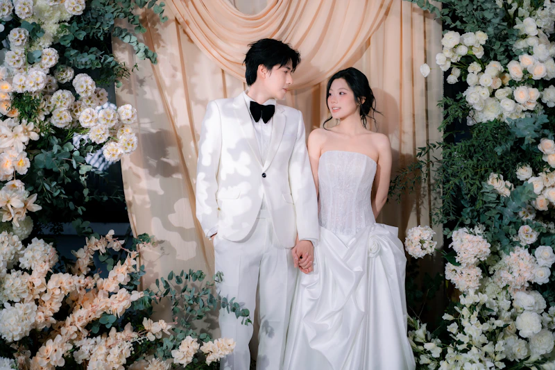 novios posando bajo un arco floral de boda