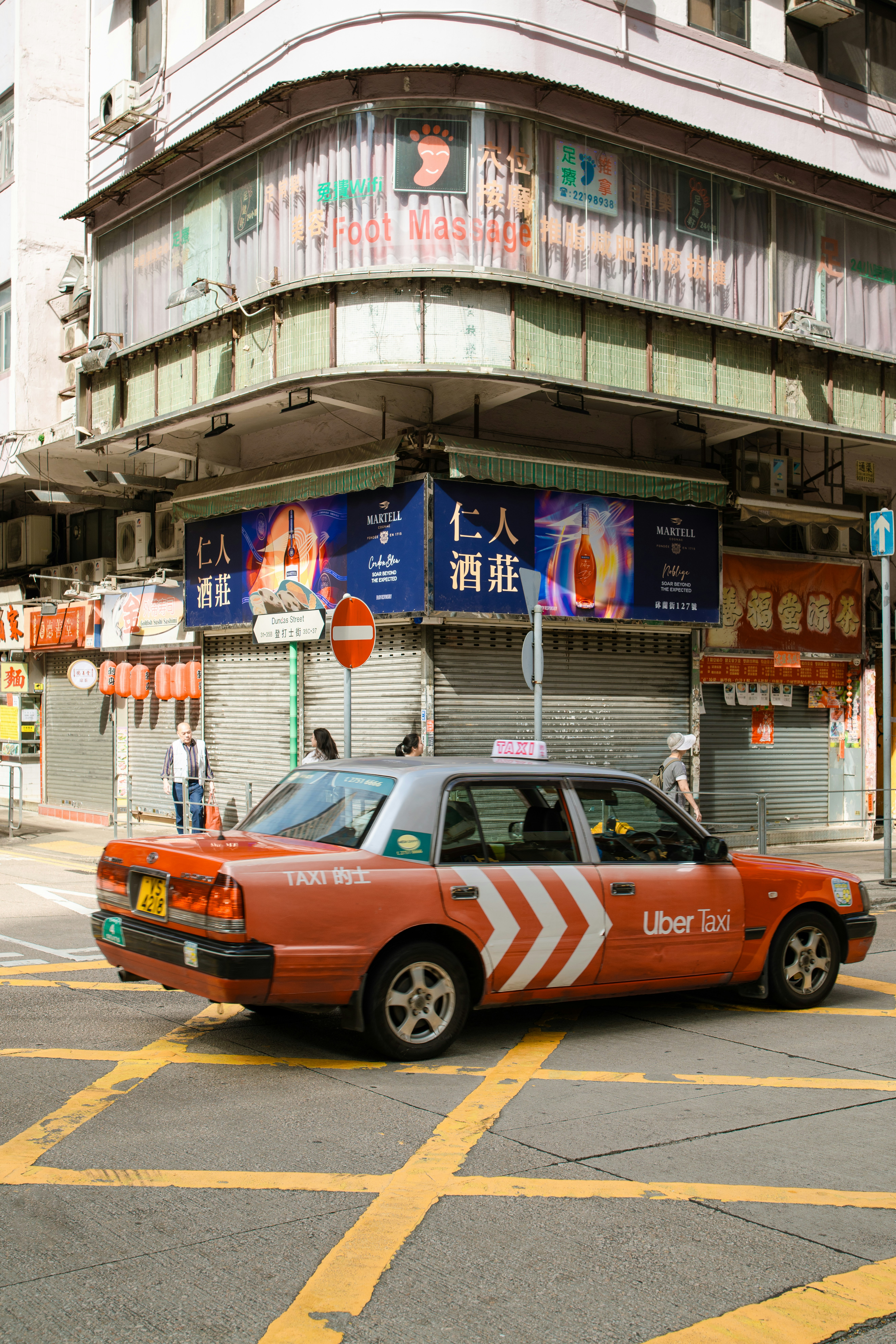 An orange uber taxi drives on a city street.