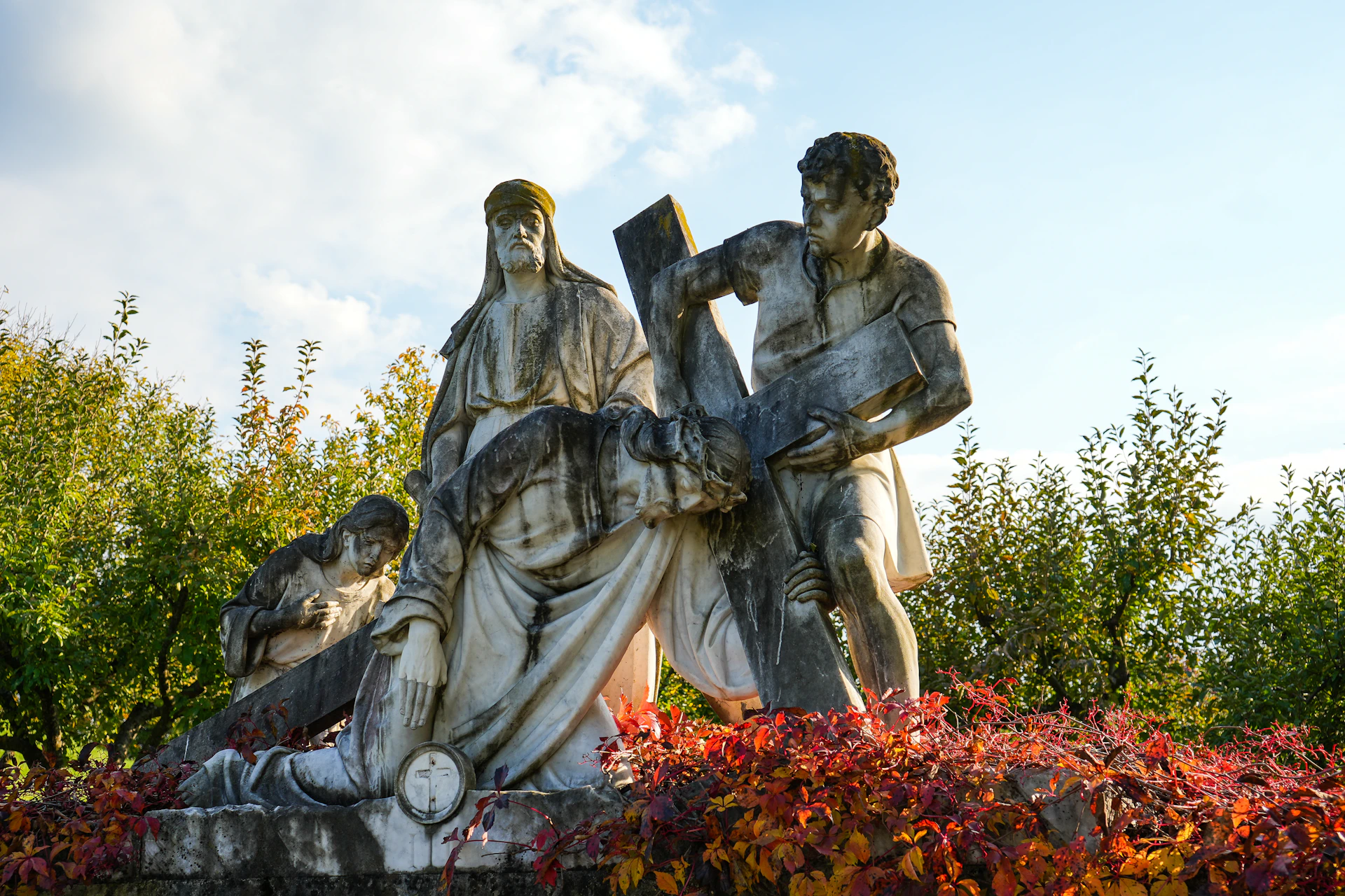 Statues depict jesus carrying the cross with onlookers.