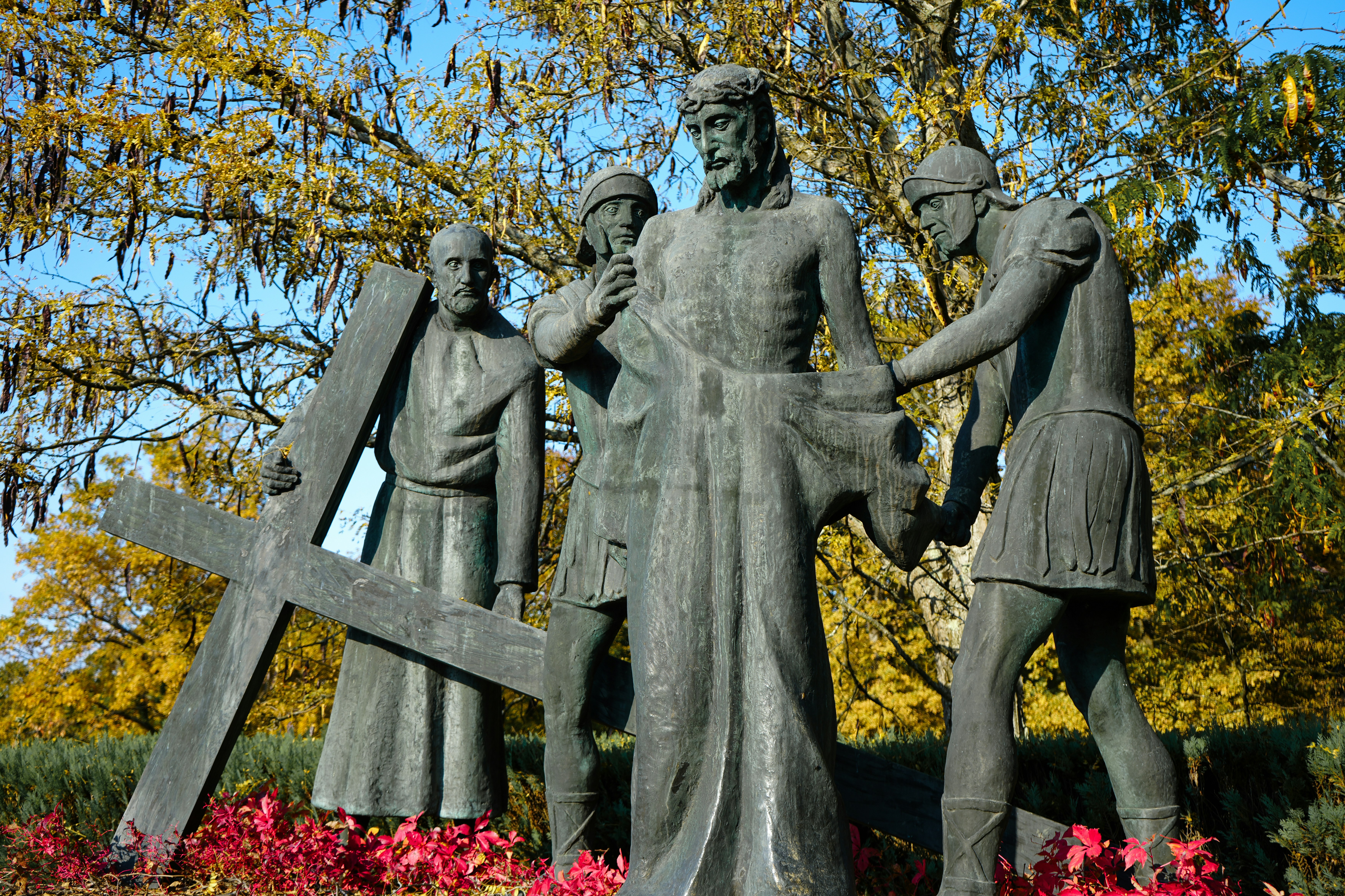 Statue of jesus carrying the cross with two men