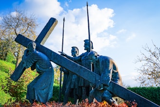 Statues depict jesus carrying the cross with soldiers.