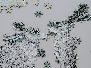 Two unfinished donkey puzzle pieces face each other.