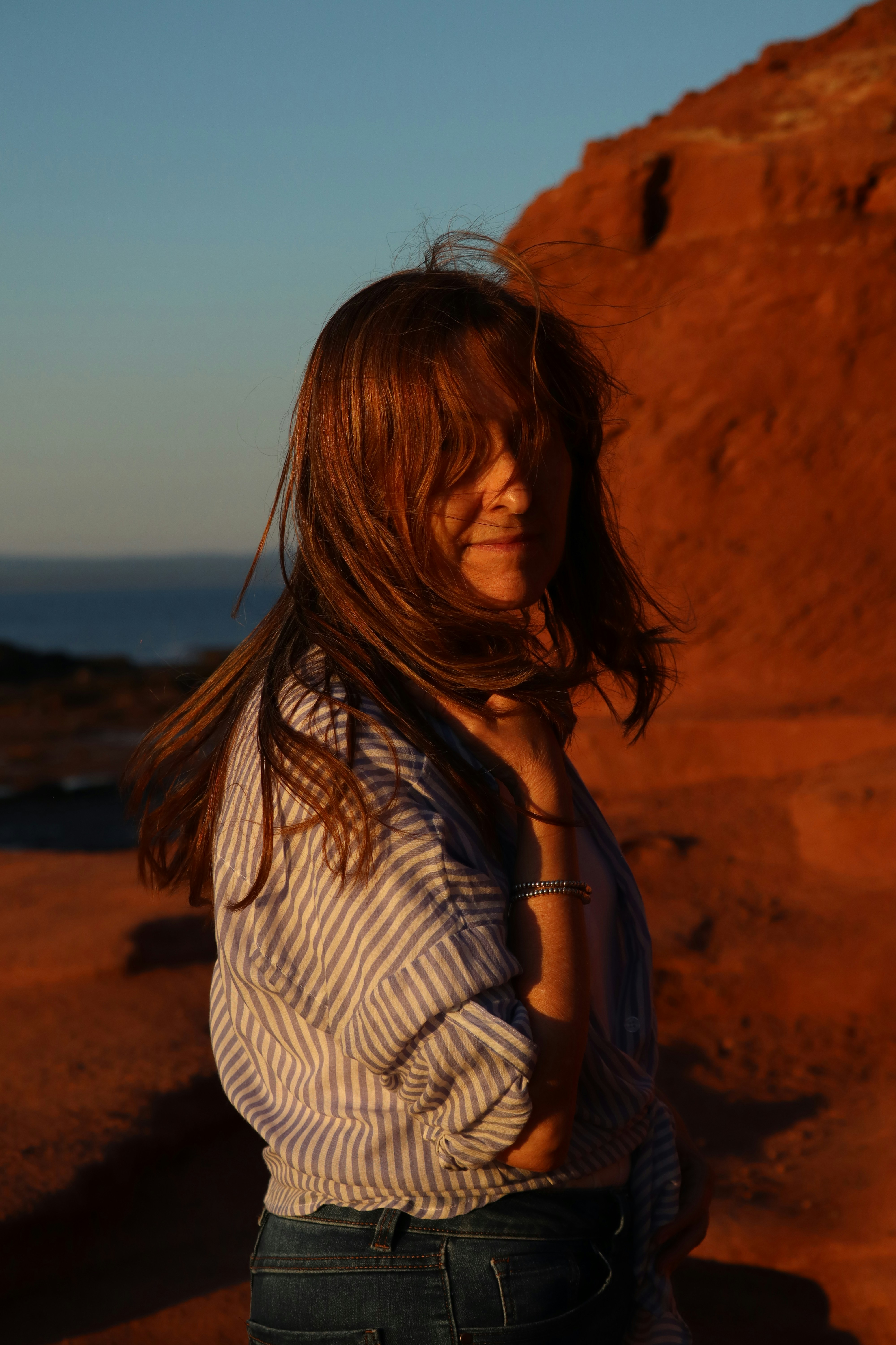 Woman with windblown hair on a rocky coastline