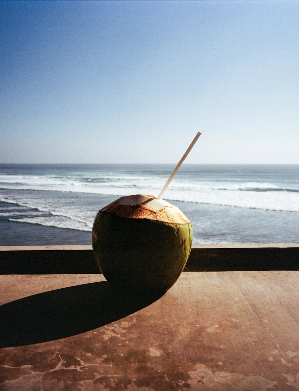 Young green coconut with a straw, opened on a Bali beach