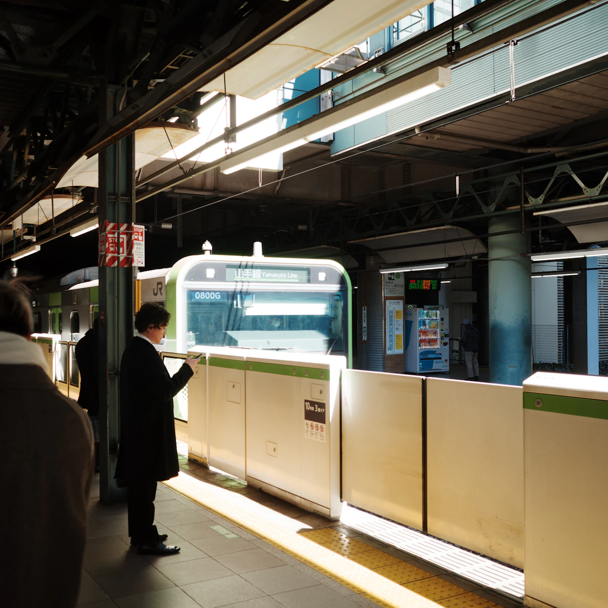 Commuters waiting on a train platform. Train commuting from Tama to central Tokyo is the standard