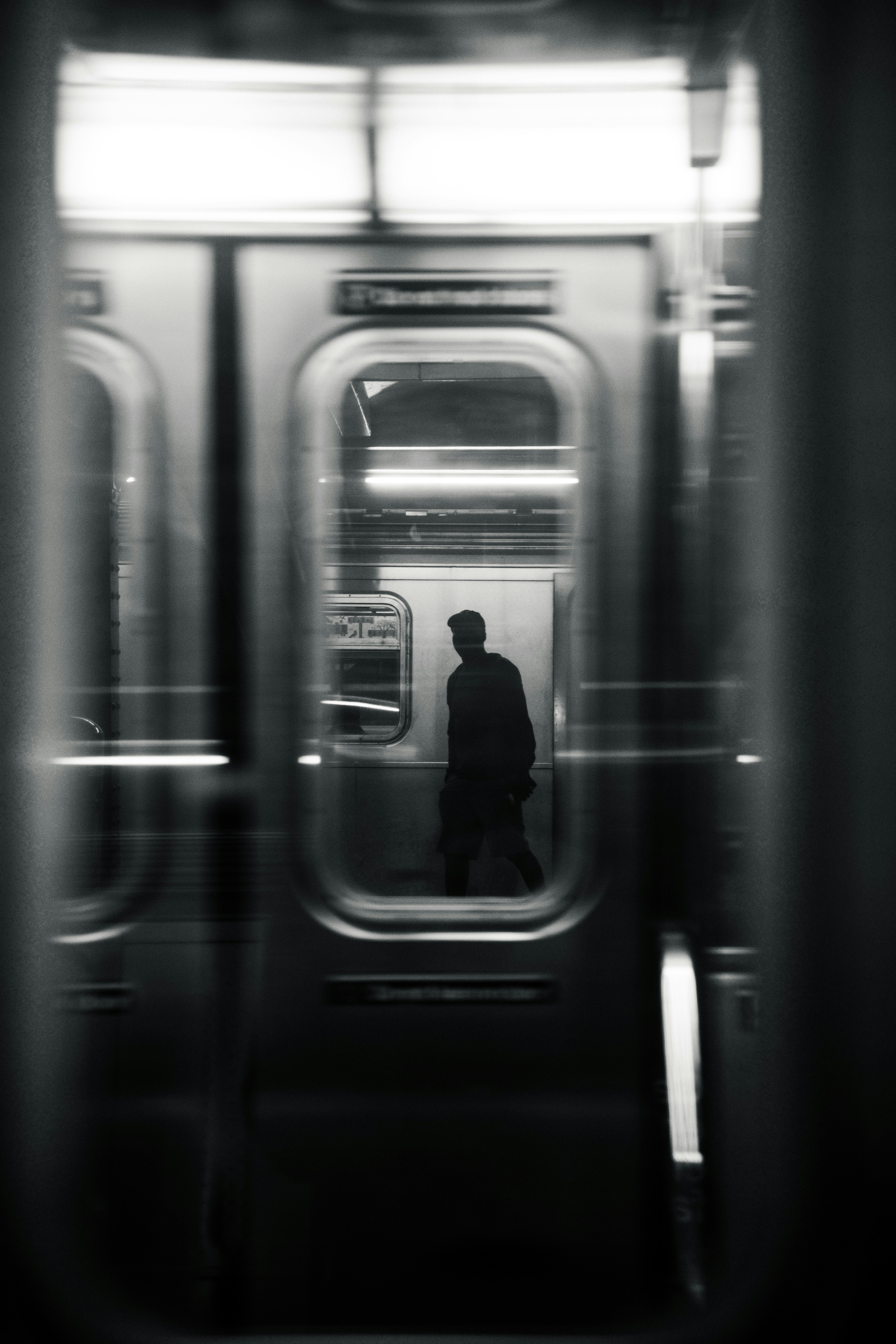 Silhouette of a man on a moving subway train.