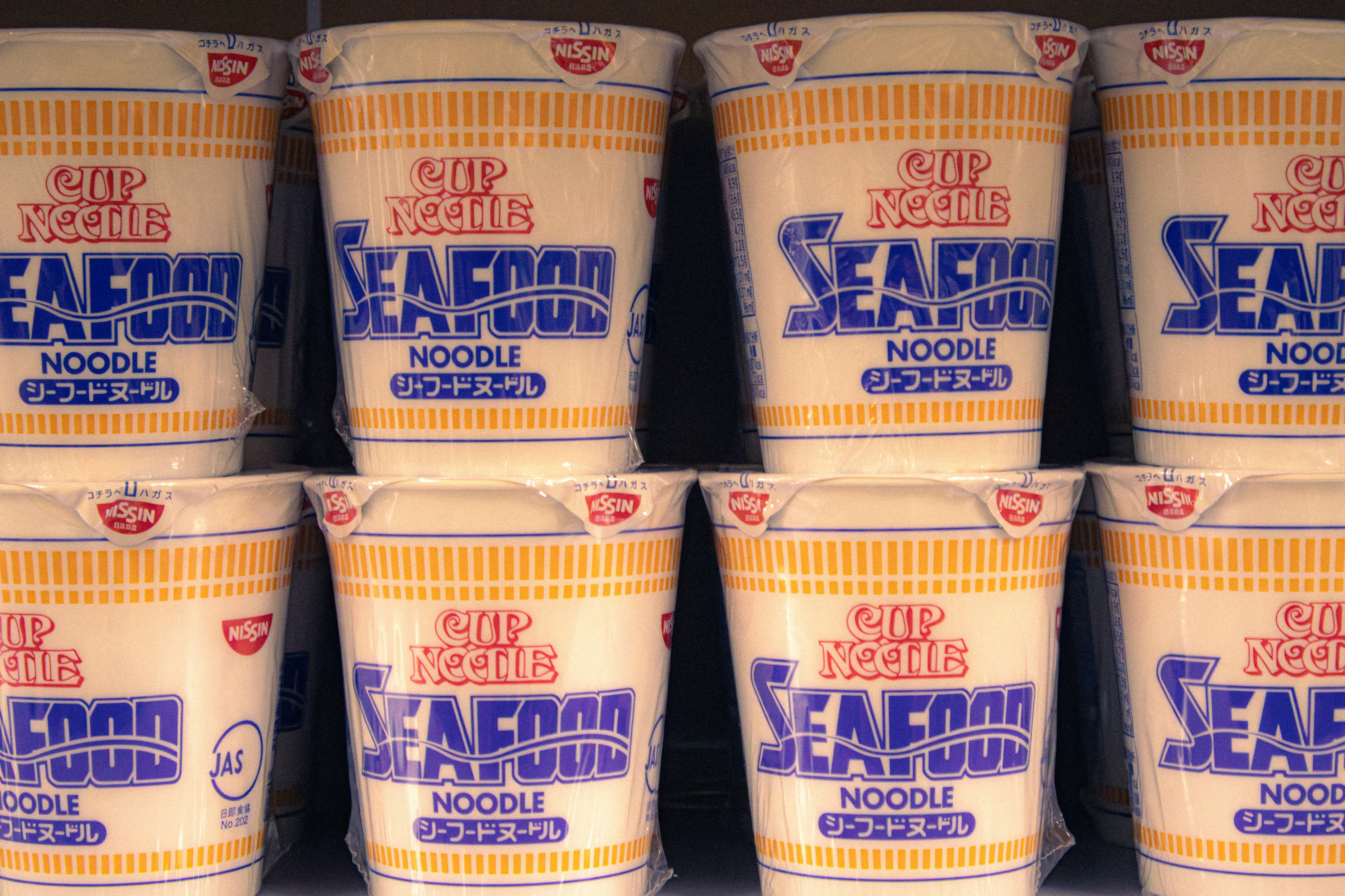 Eight cups of seafood noodle soup stacked.