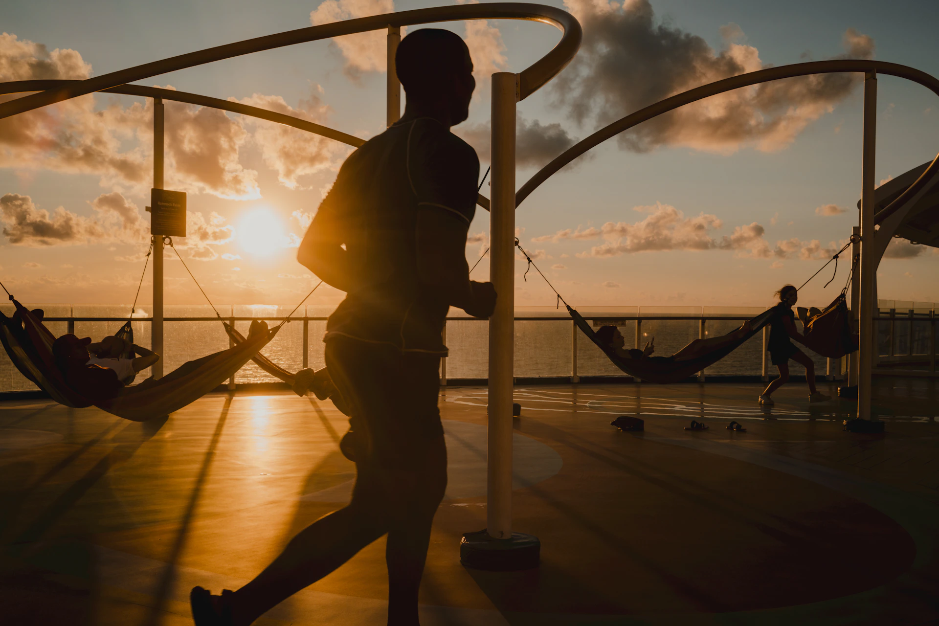 Man running on deck with hammocks at sunset