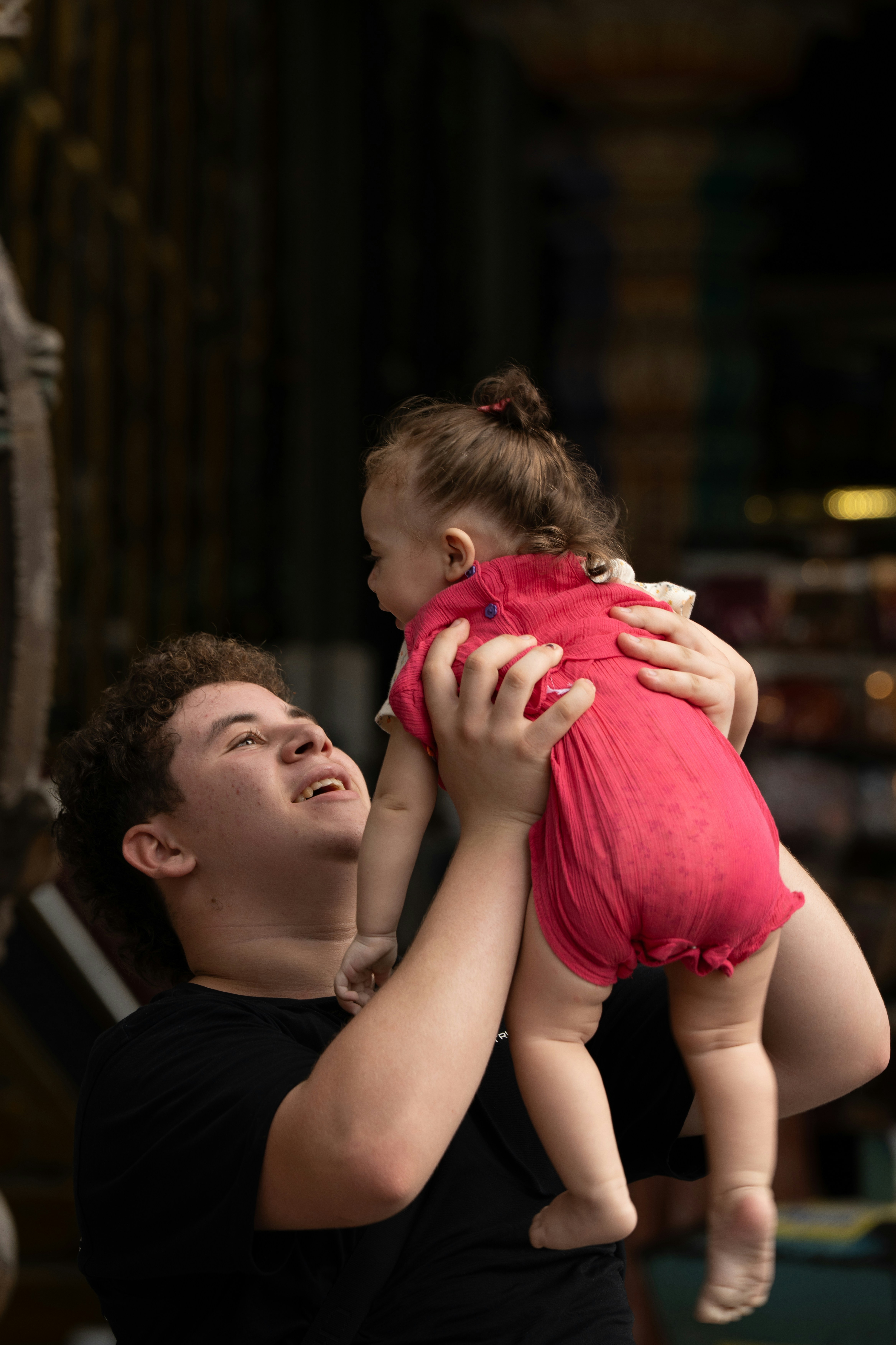 Young man holds a baby girl up high