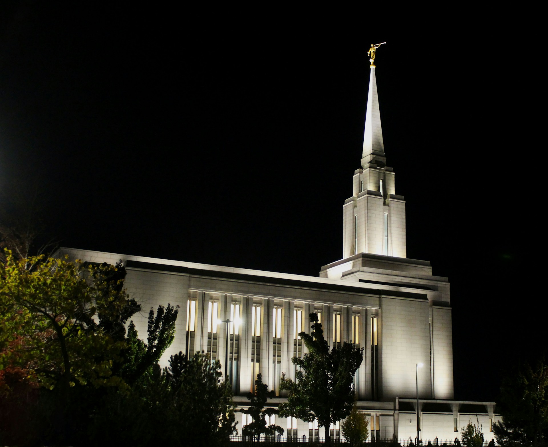 A brightly lit temple at night with a spire.