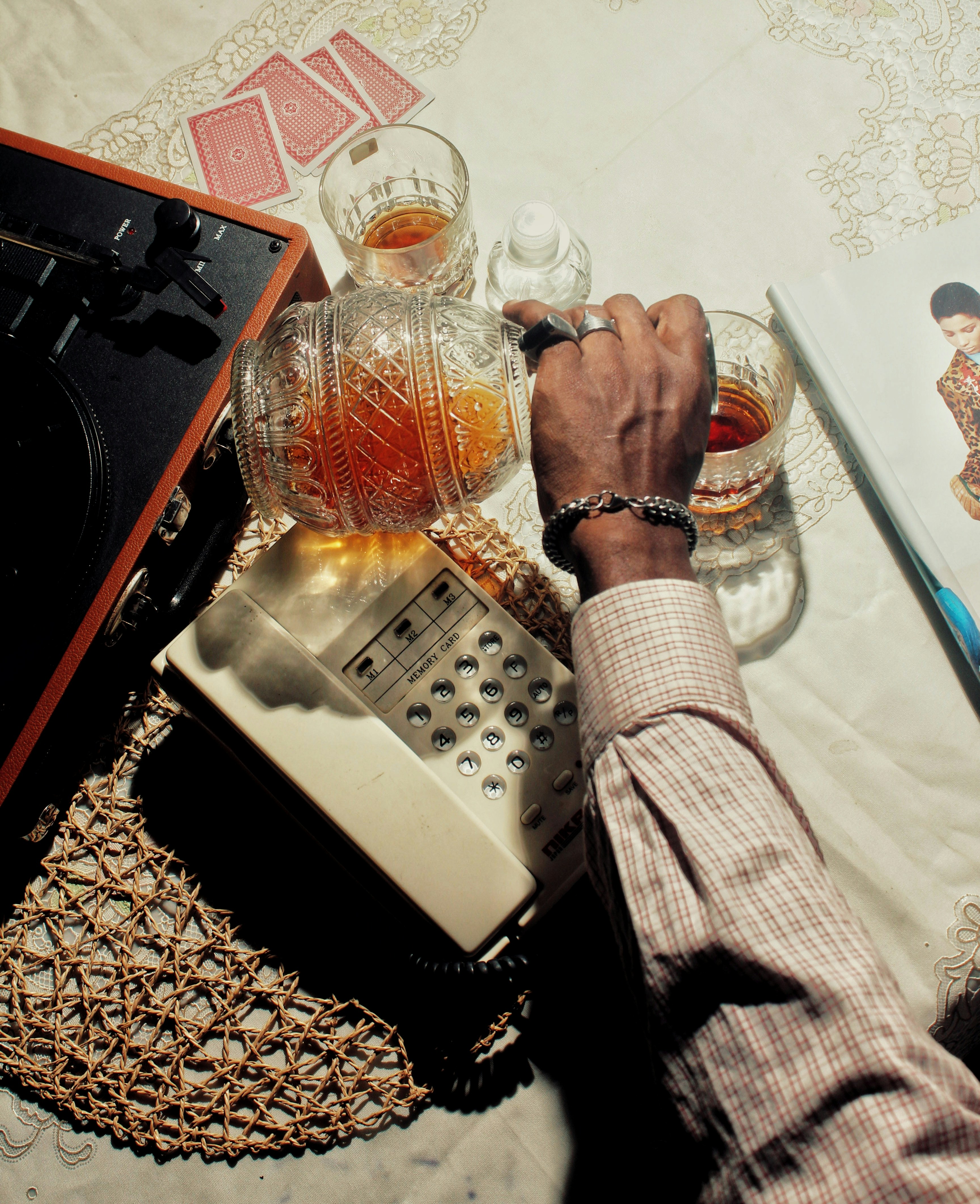 A high-angle shot of a bartender pouring whiskey into a glass with a large ice cube.