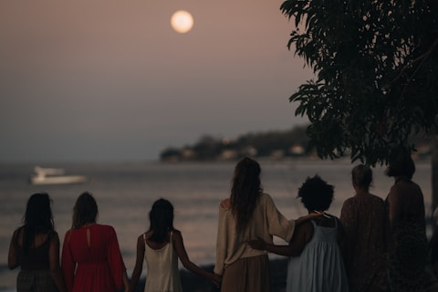 Group of women watching the moon over the ocean.