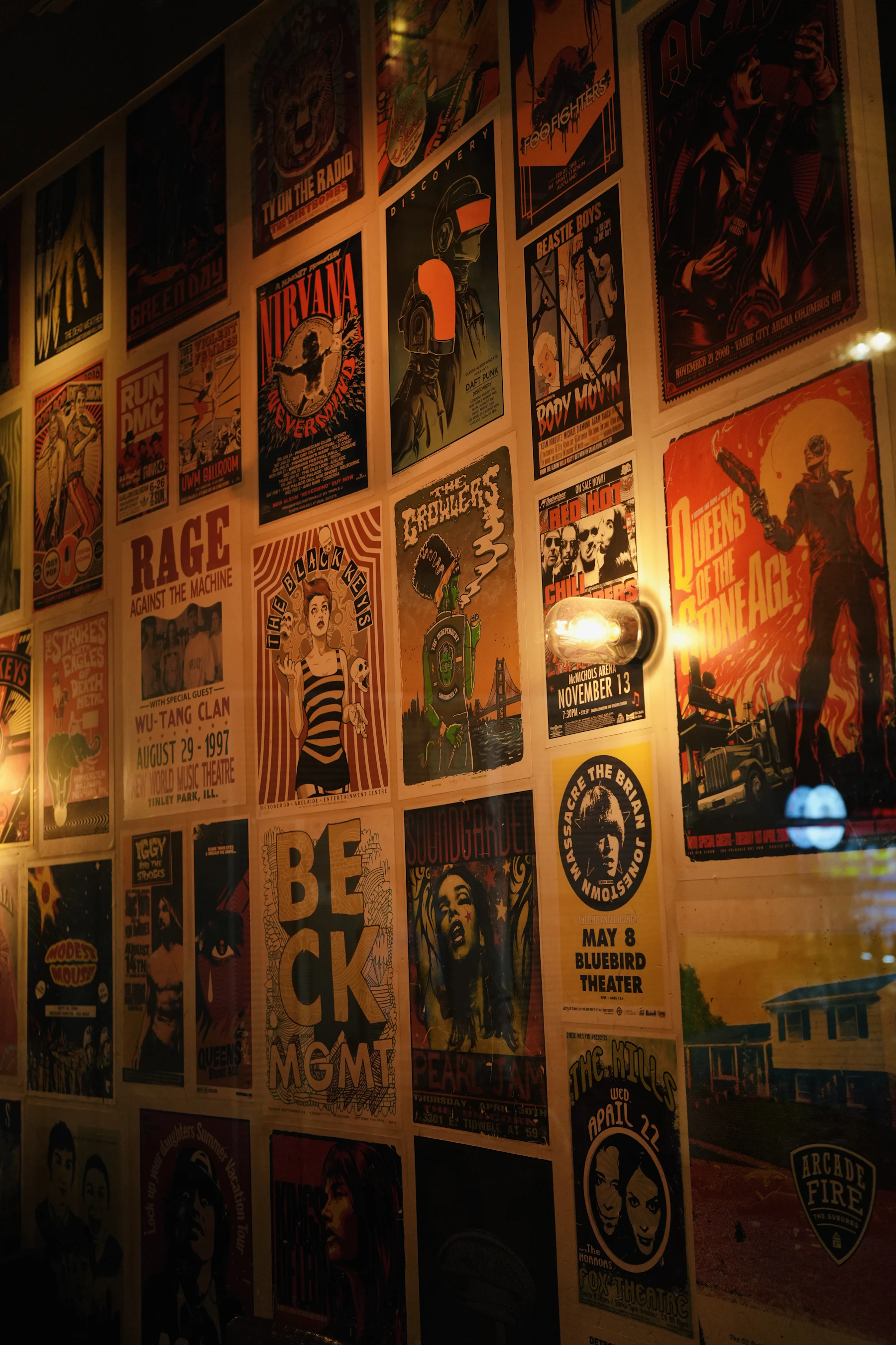 A dim wall papered edge to edge with screen-printed concert posters