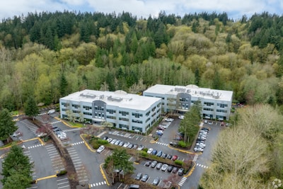 Two modern office buildings surrounded by lush green forest.