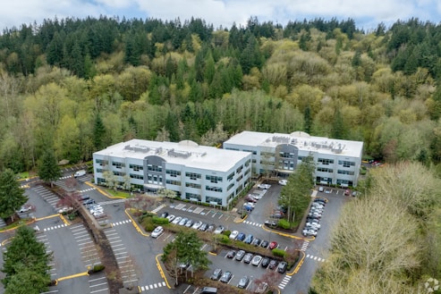 Two modern office buildings surrounded by lush green forest.