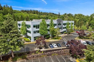 Modern office building surrounded by lush green trees.
