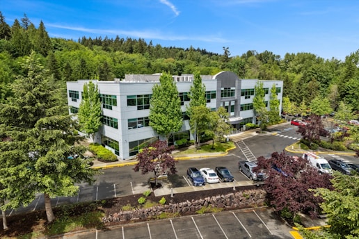 Modern office building surrounded by lush green trees.