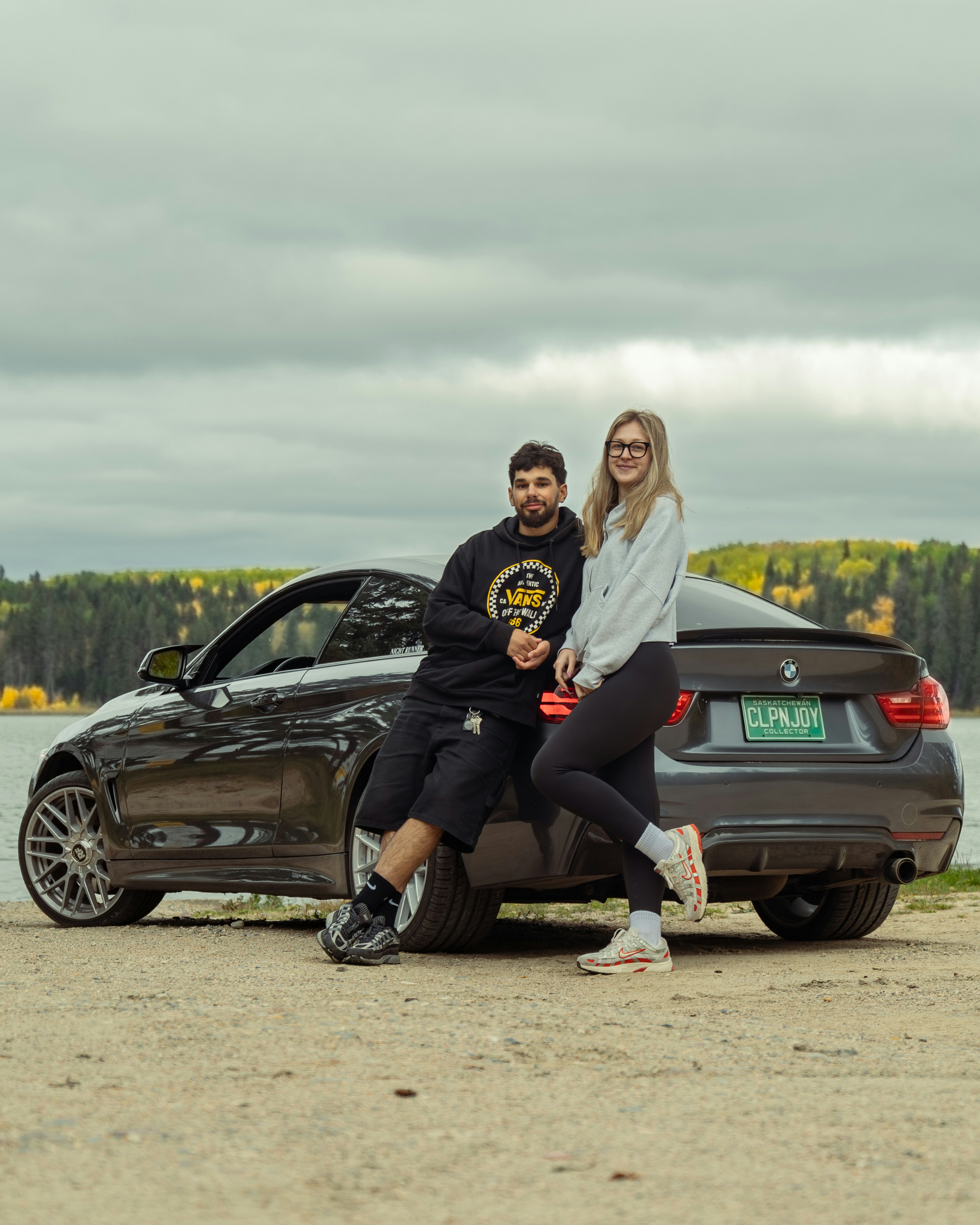 Couple leaning on a car by a lake