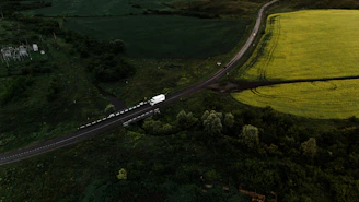 Truck driving on a road through green fields