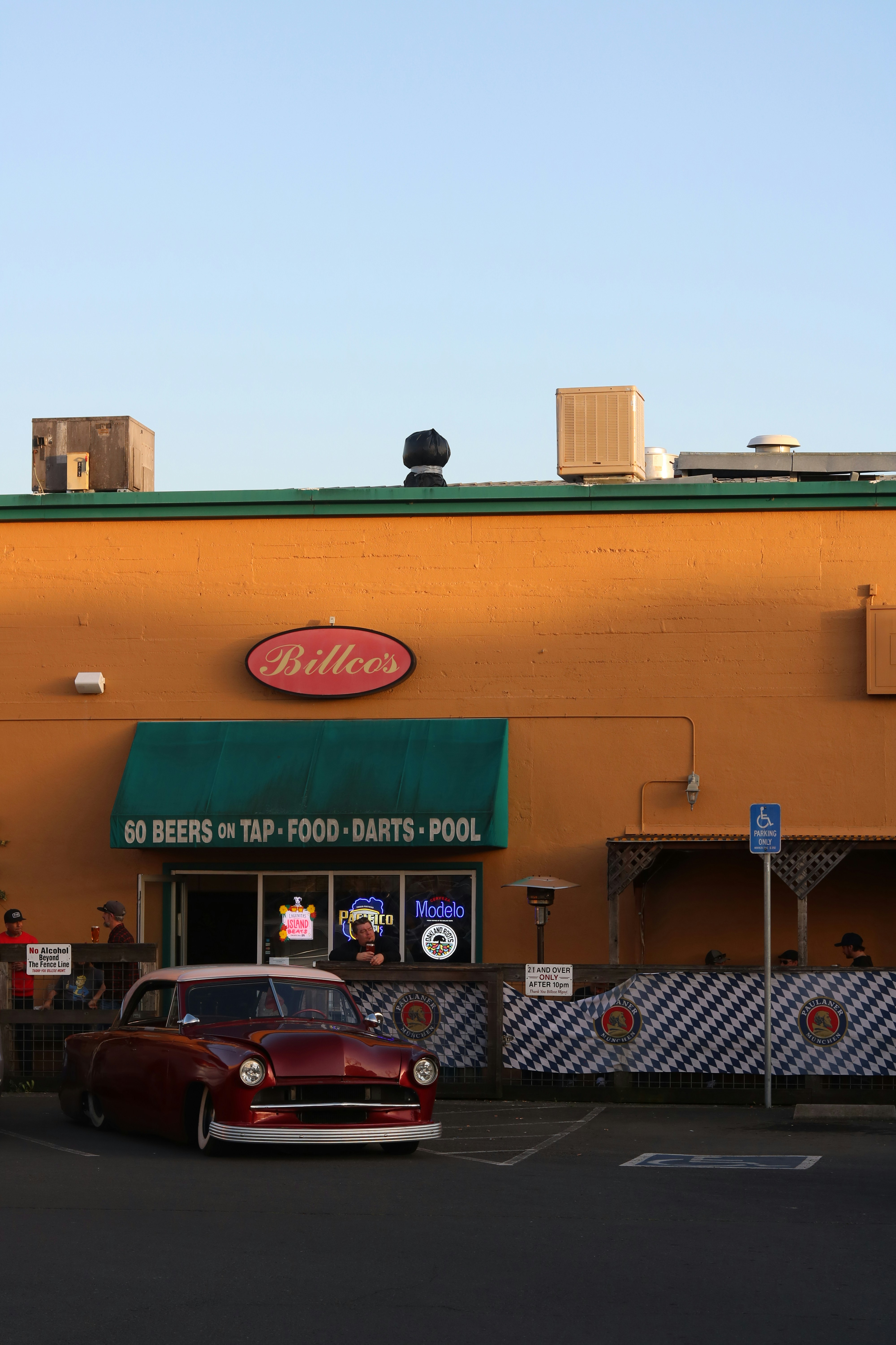 Classic car parked outside a bar with outdoor seating