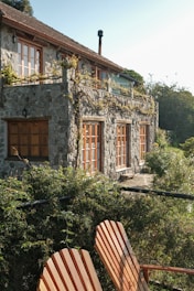 Stone house with wooden windows and lush greenery