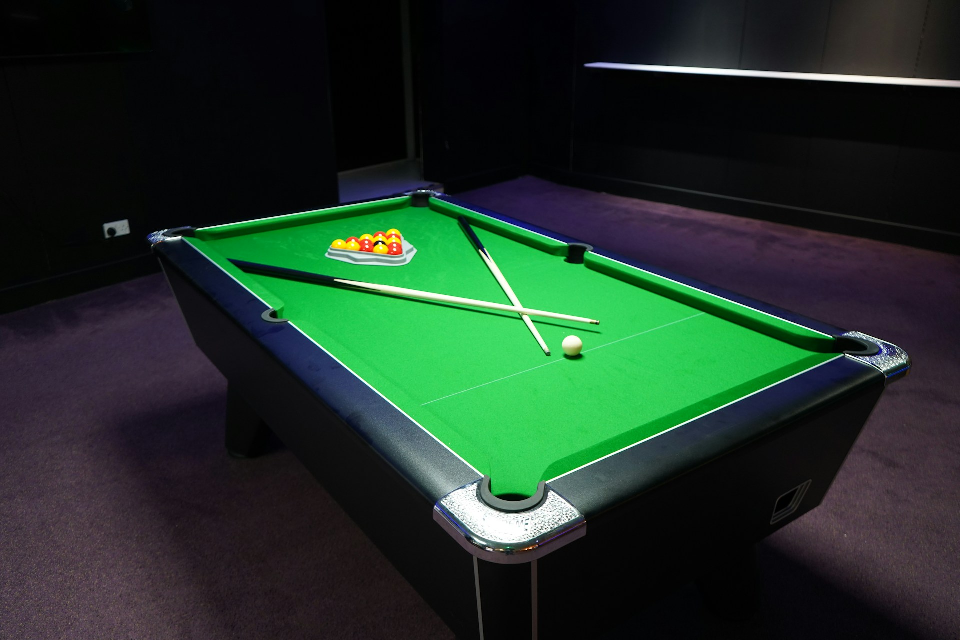 A green pool table with balls and cues.