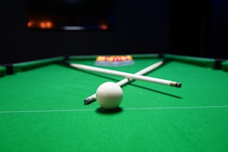 Two pool cues crossed over a white ball