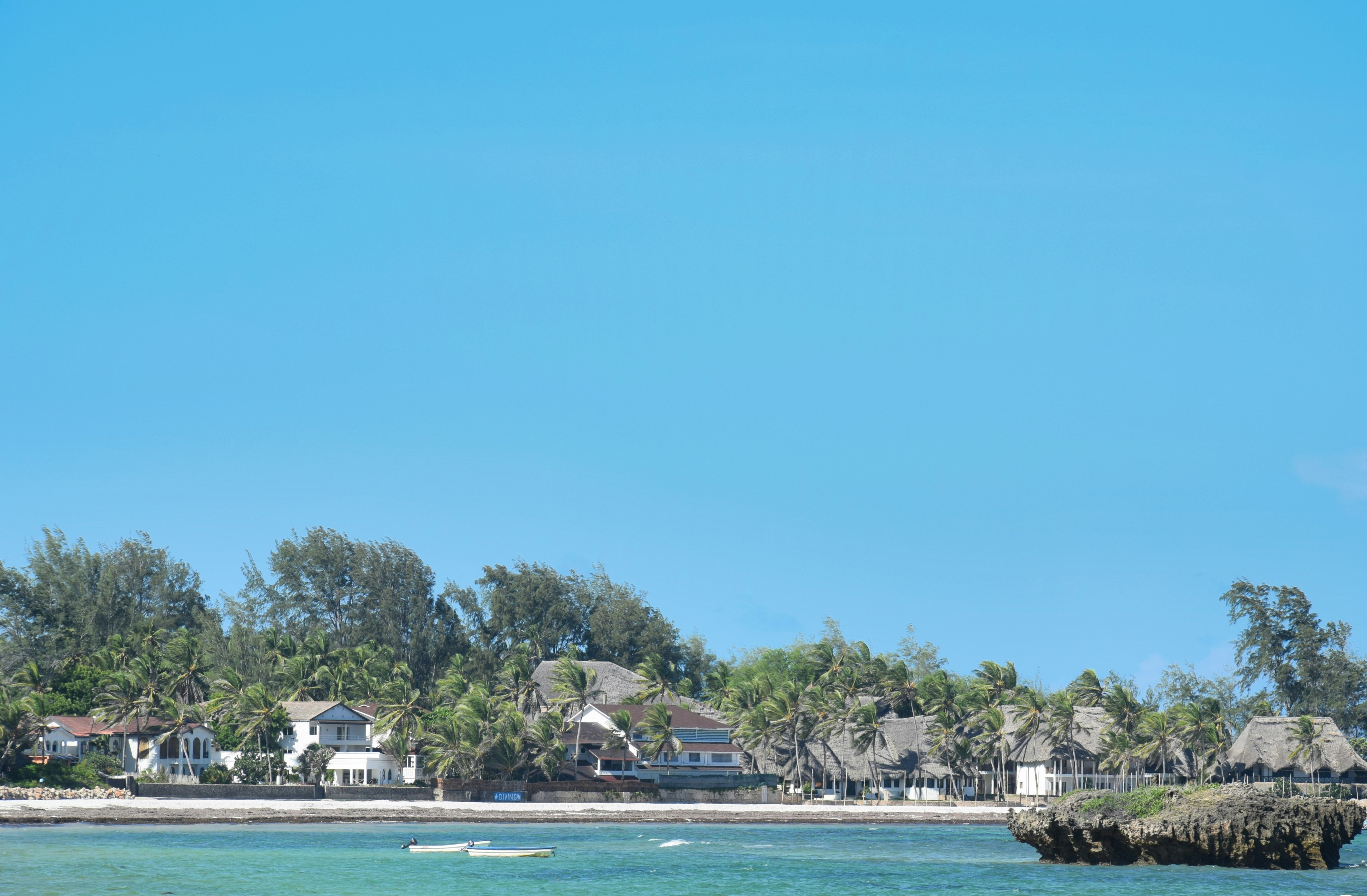 Tropical resort buildings along a sandy beach.