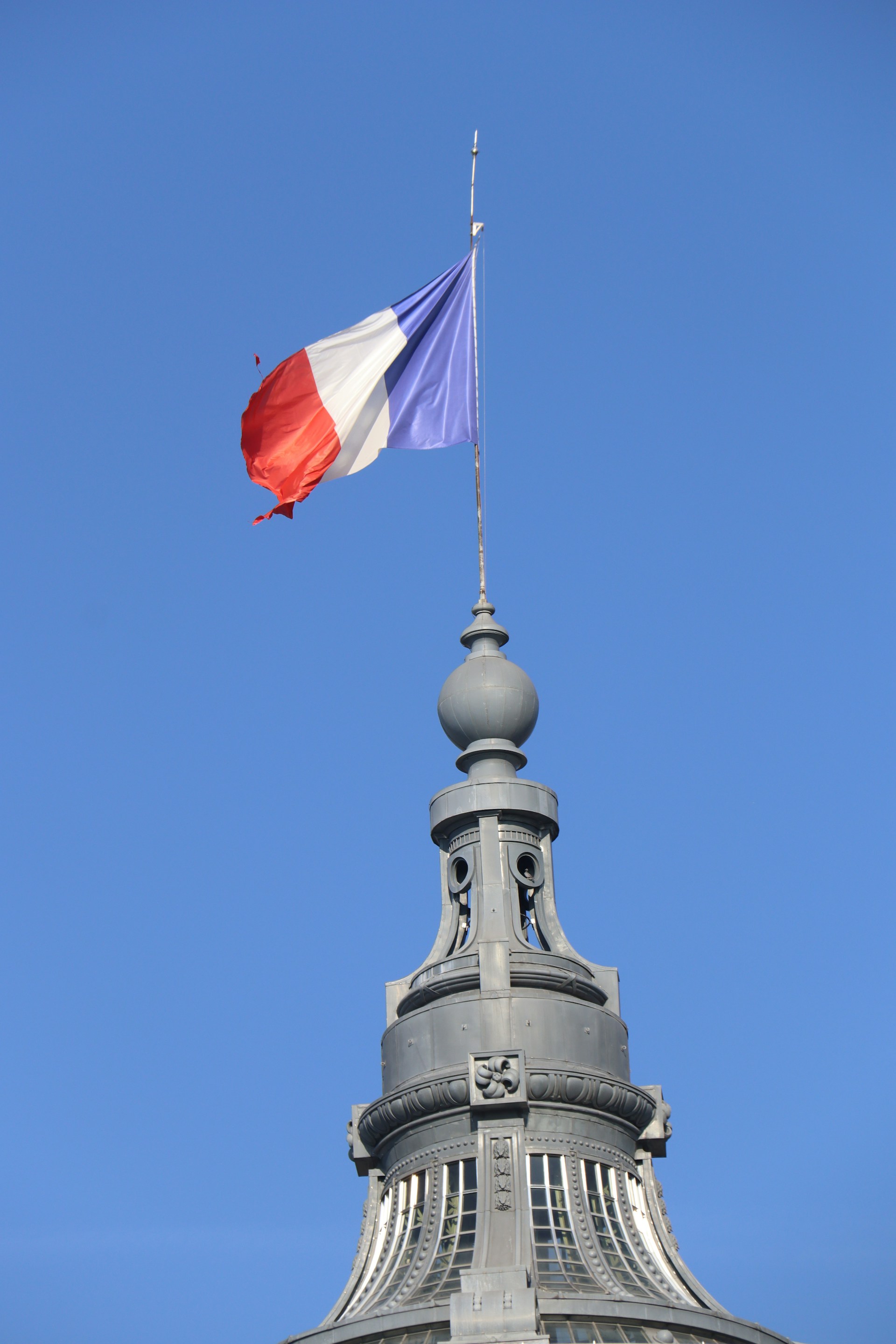 French flag flying atop a building spire.