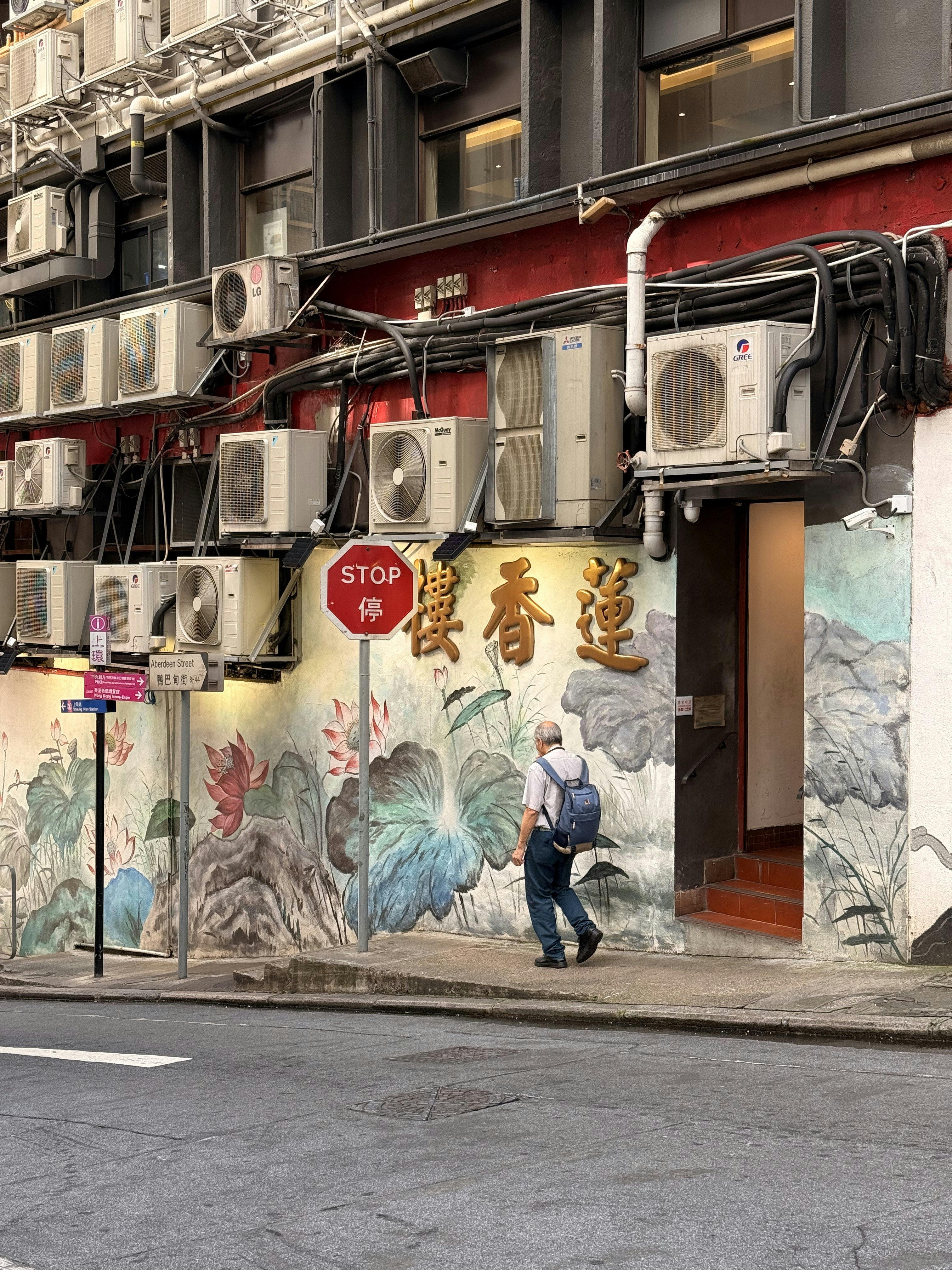 Man walks past mural with air conditioners above