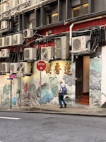 Man walks past mural with air conditioners above