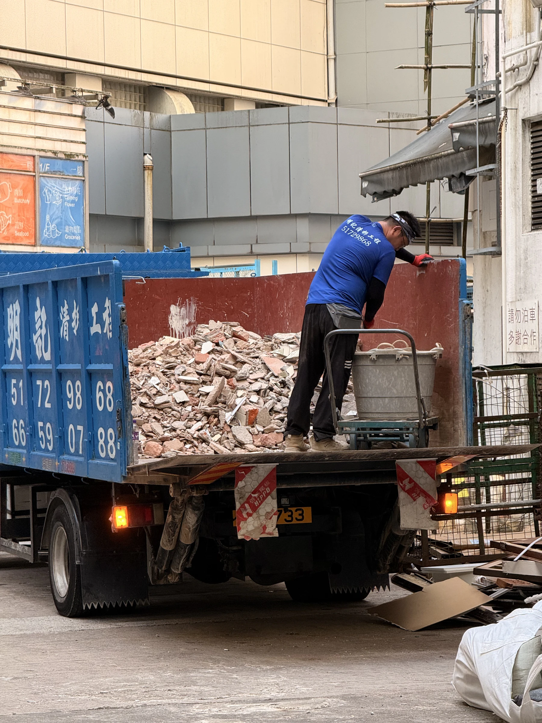 Worker loading renovation debris into a hauling truck