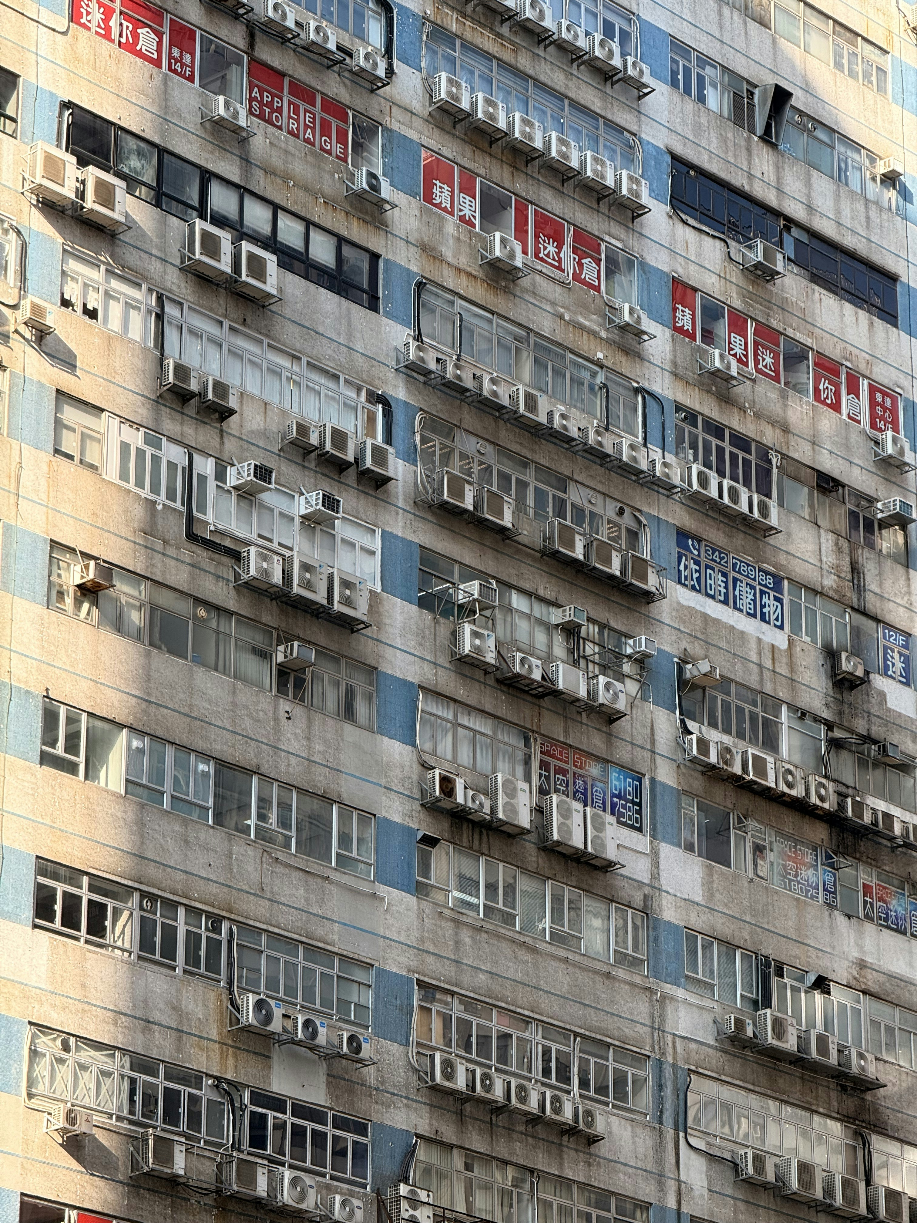 Apartment building facade with many air conditioning units.