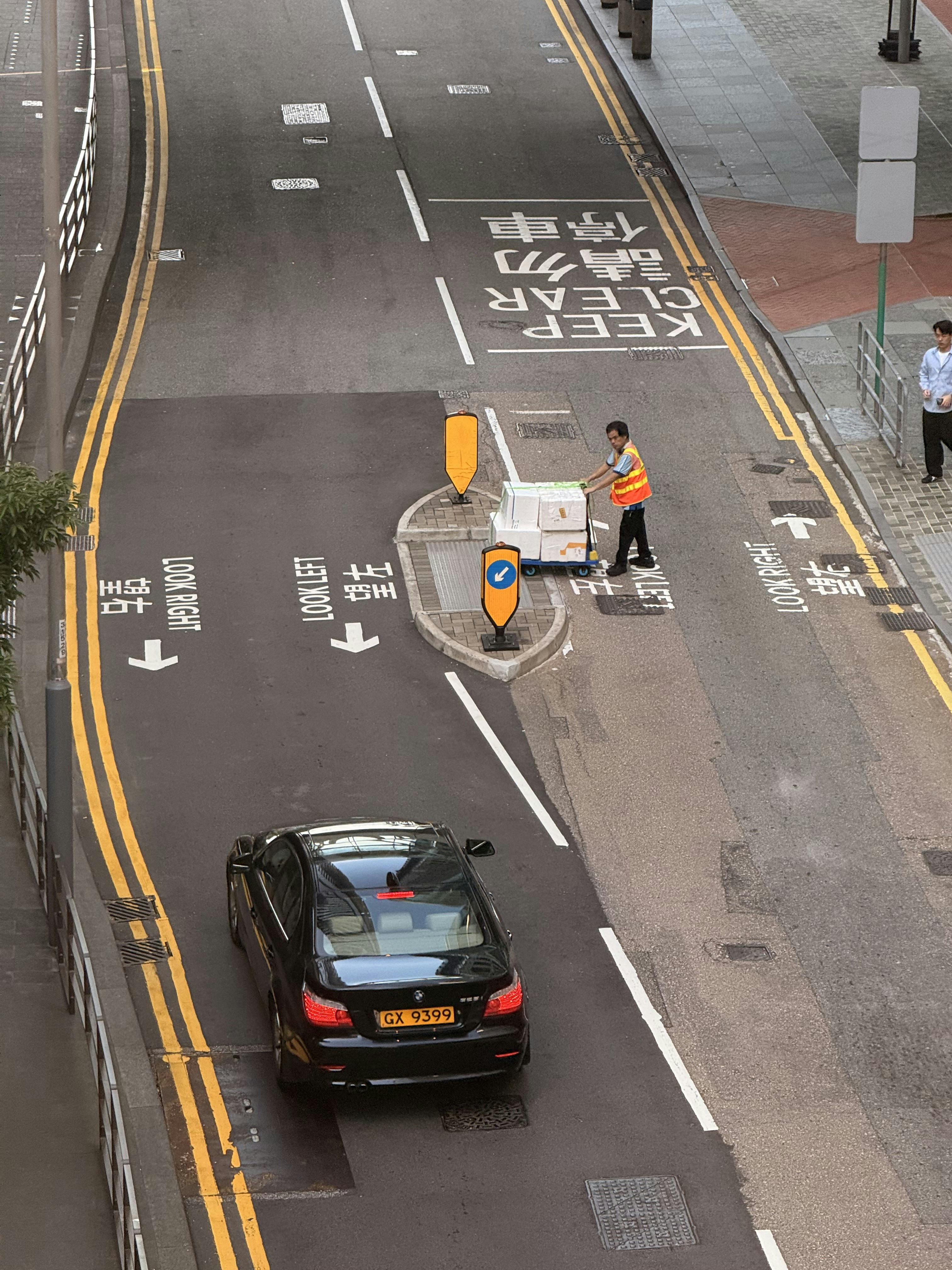 Man pushing cart on city street with car