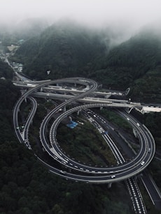 Complex highway interchange surrounded by misty green mountains.