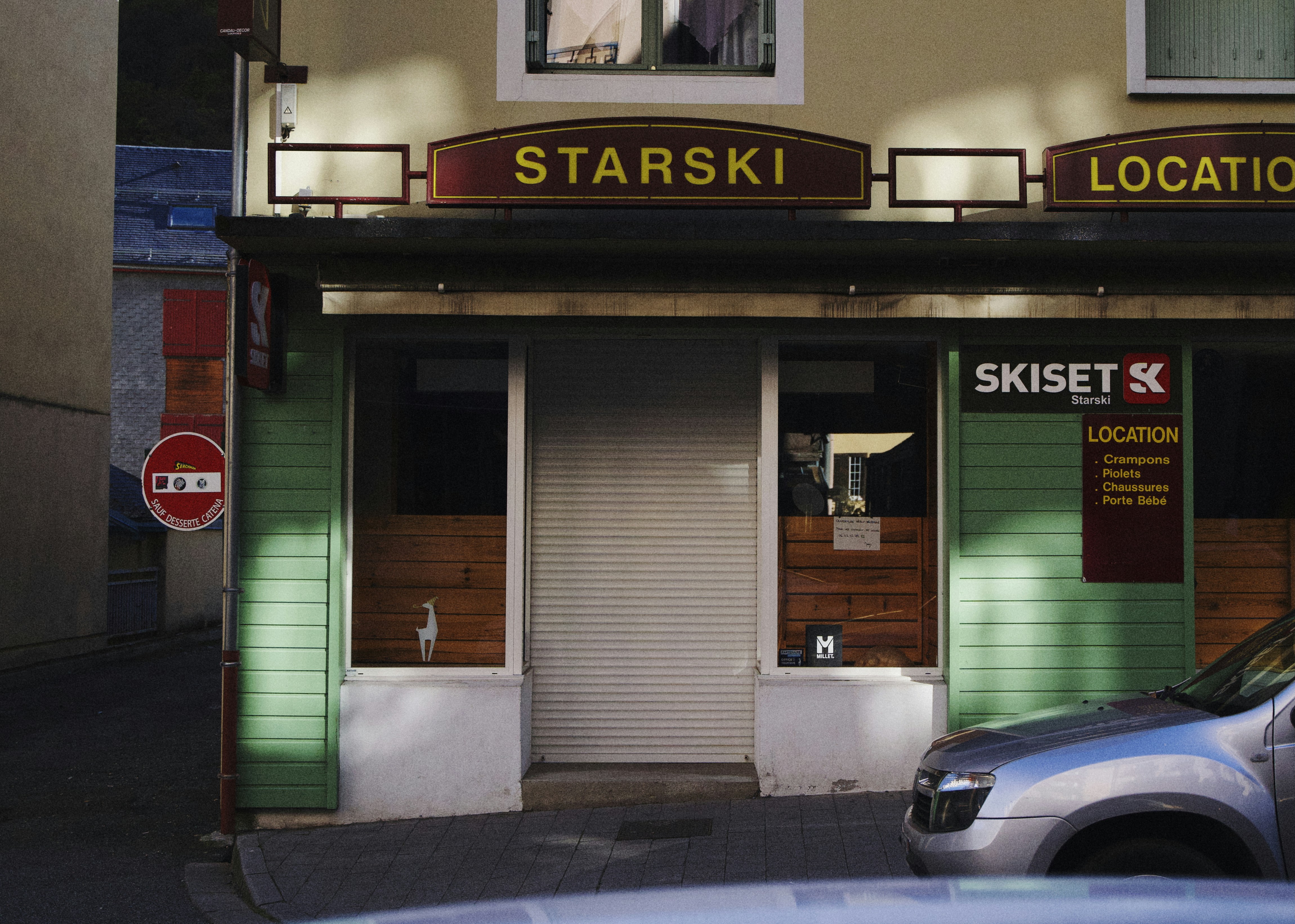 Tienda de alquiler de esquís con coche aparcado en el exterior