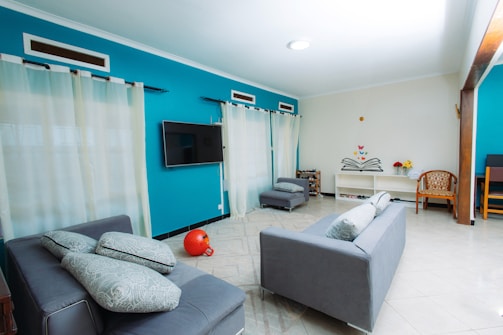 Modern living room with teal walls and gray sofas.