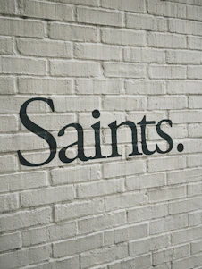The word saints written on a white brick wall.