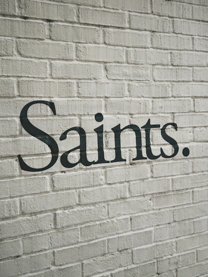 The word saints written on a white brick wall.