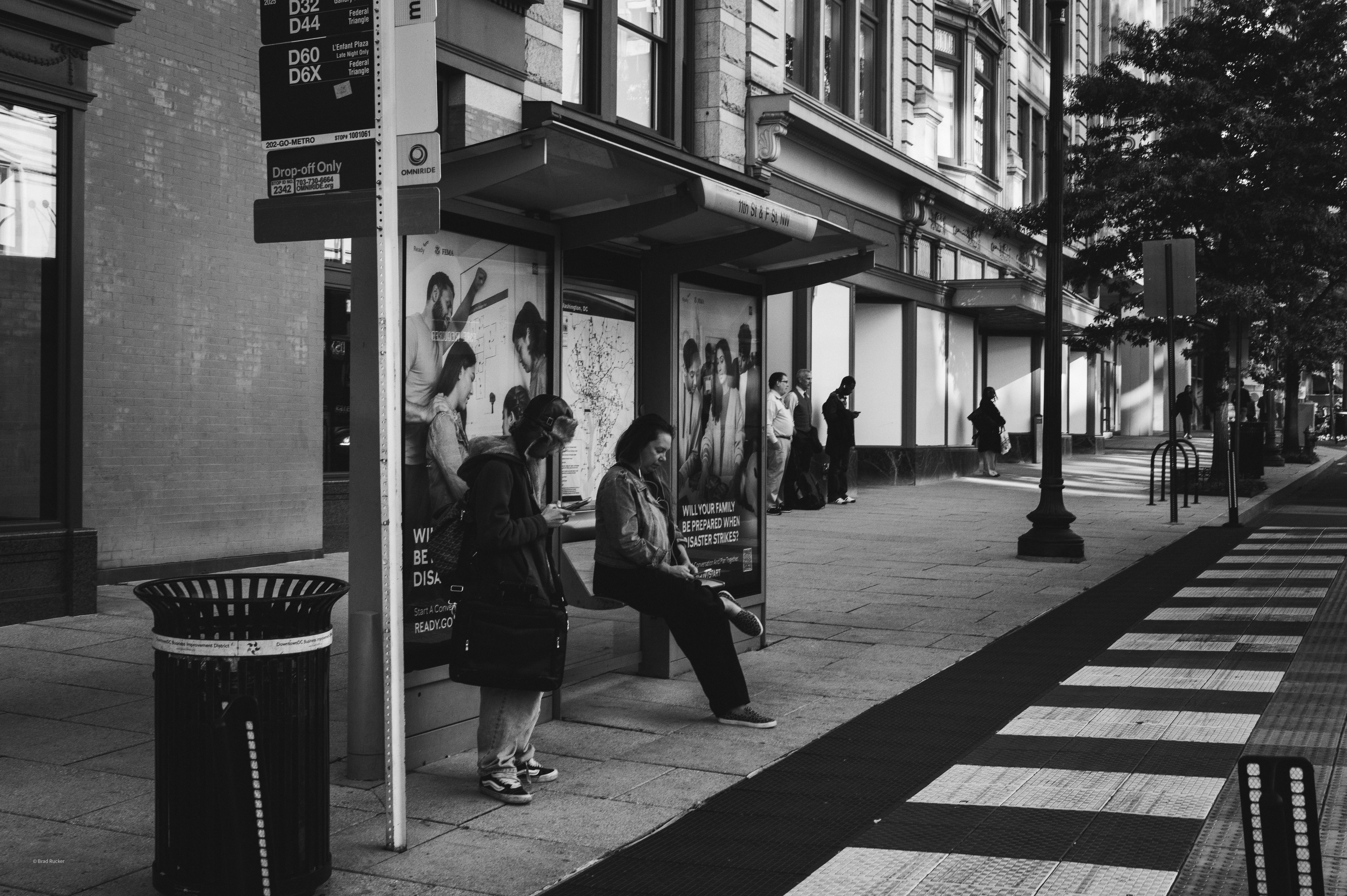 People waiting at a bus stop on a city street.