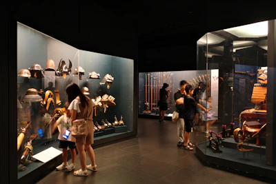 People viewing historical armor and weapons in a museum.