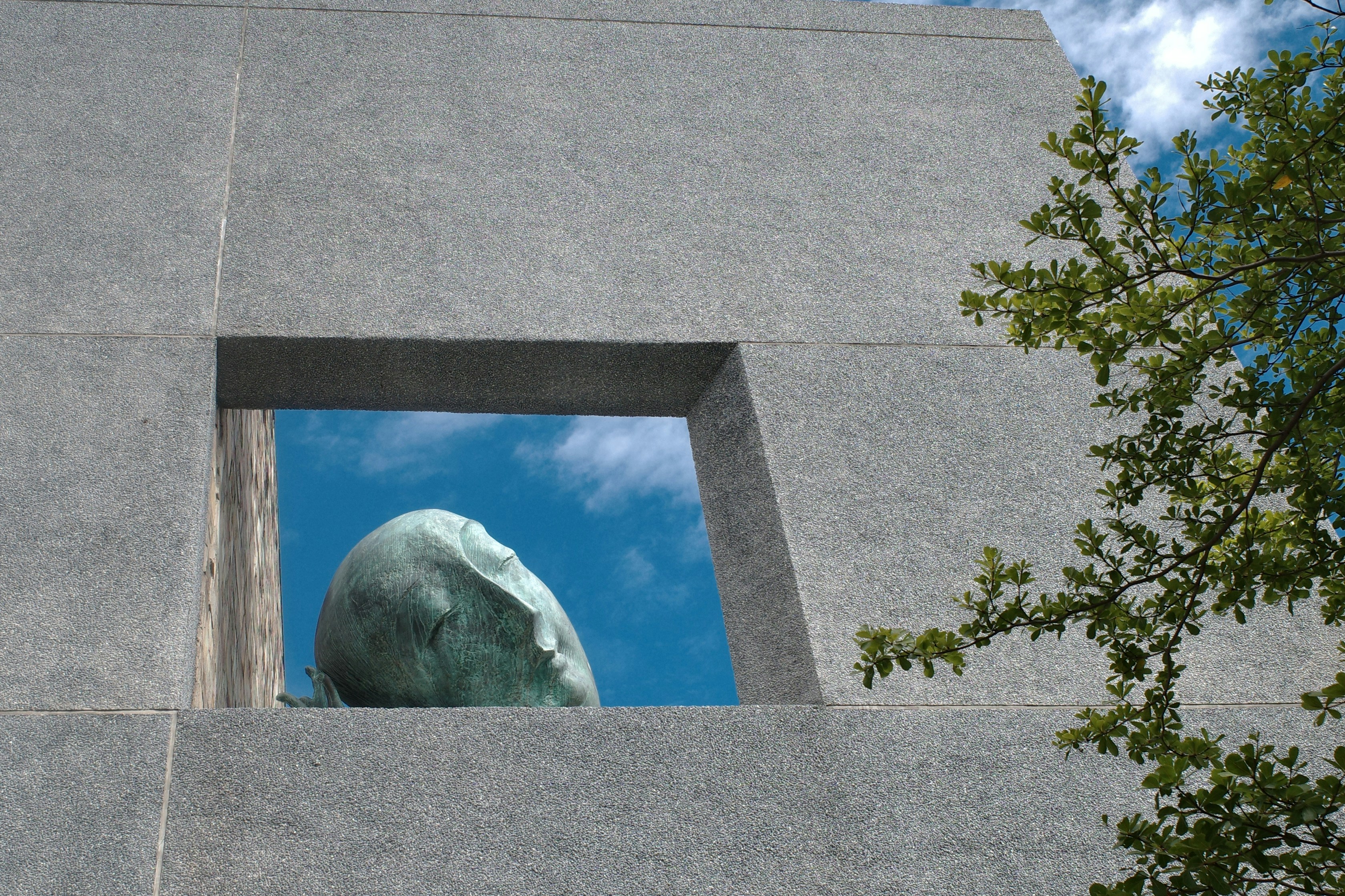 Sculpture head framed by concrete window against sky
