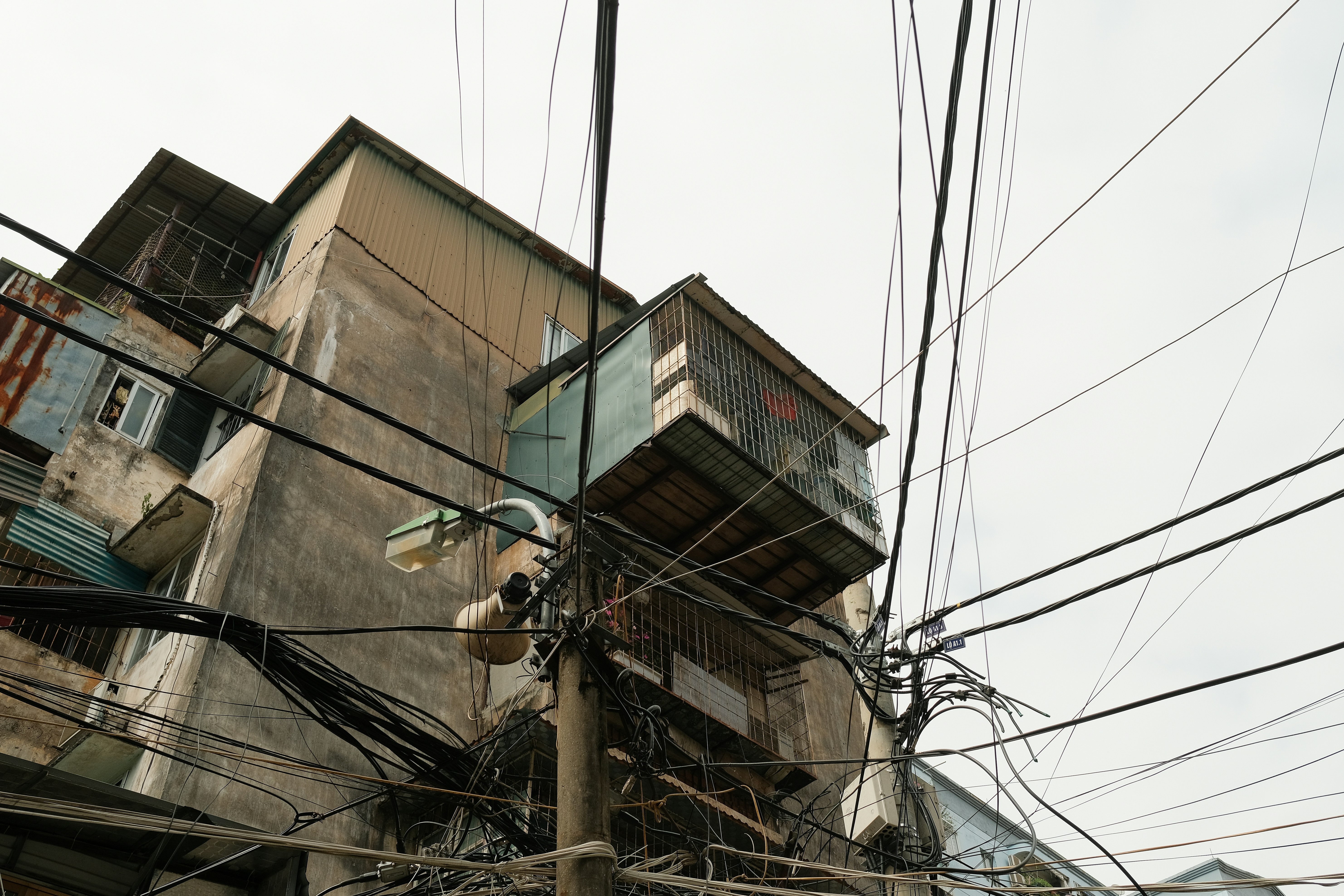 Tangled wires obscure old buildings under a pale sky.
