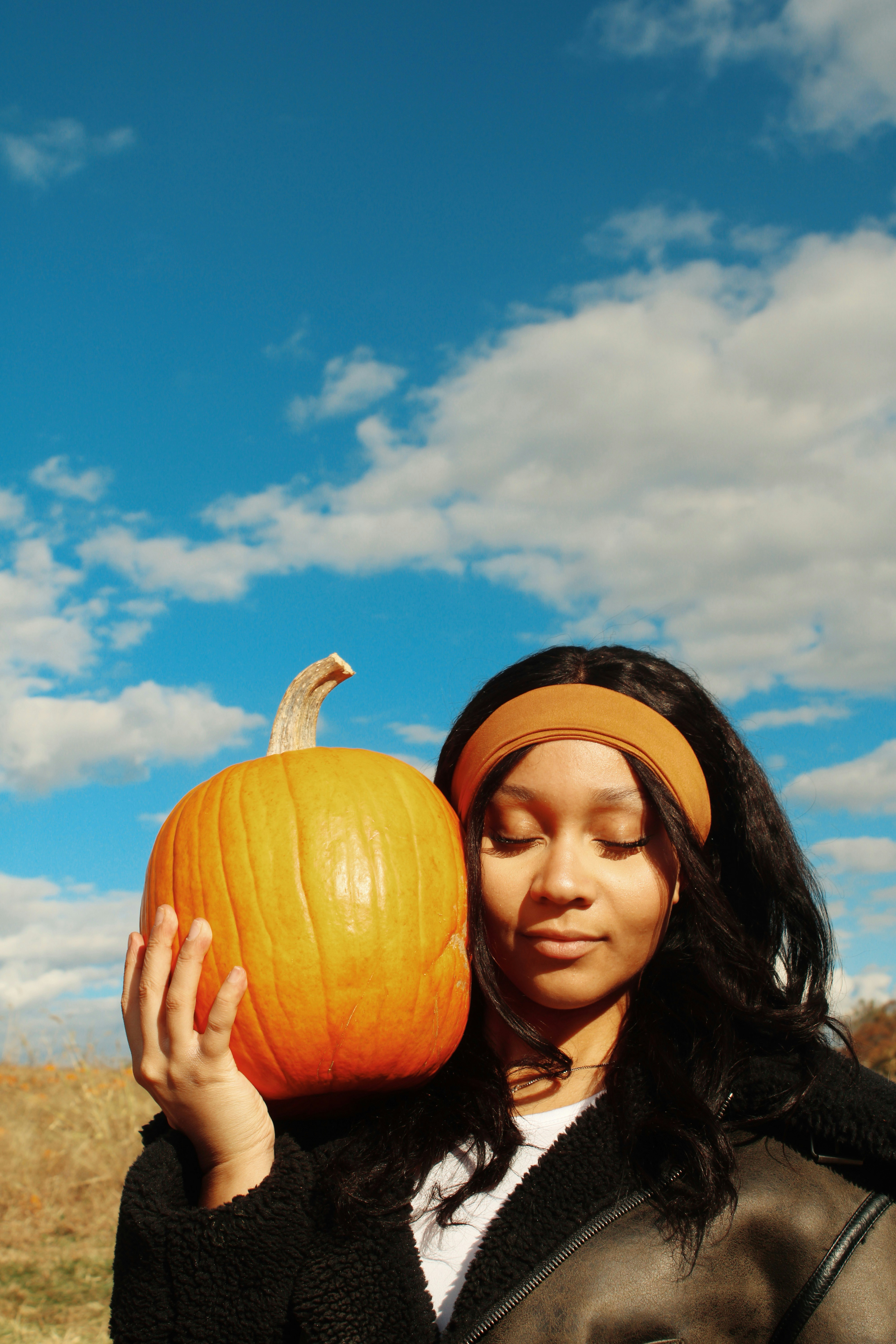 Woman holding a pumpkin against a blue sky