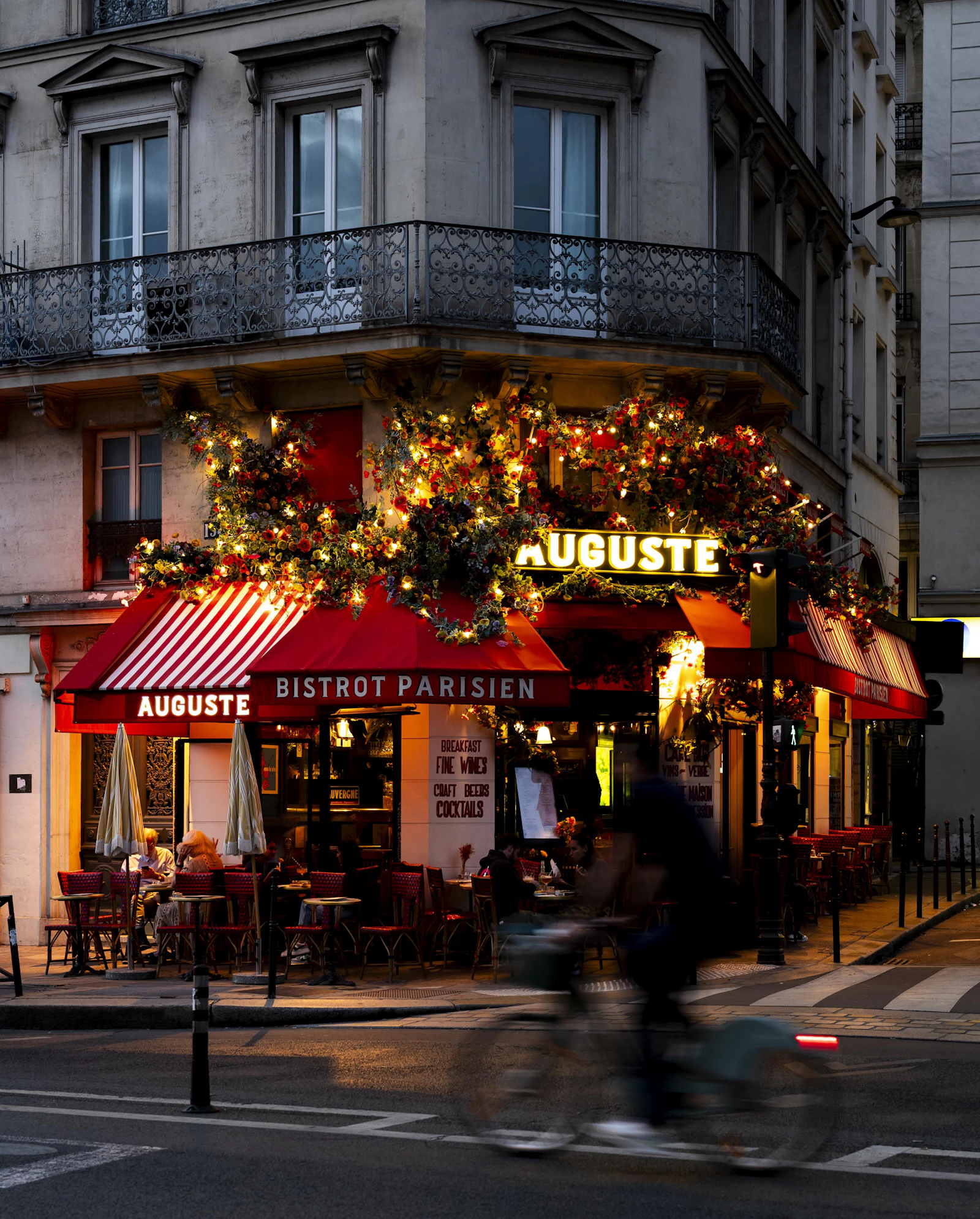 Bistrot animé en soirée avec guirlandes lumineuses et terrasse pleine de vie