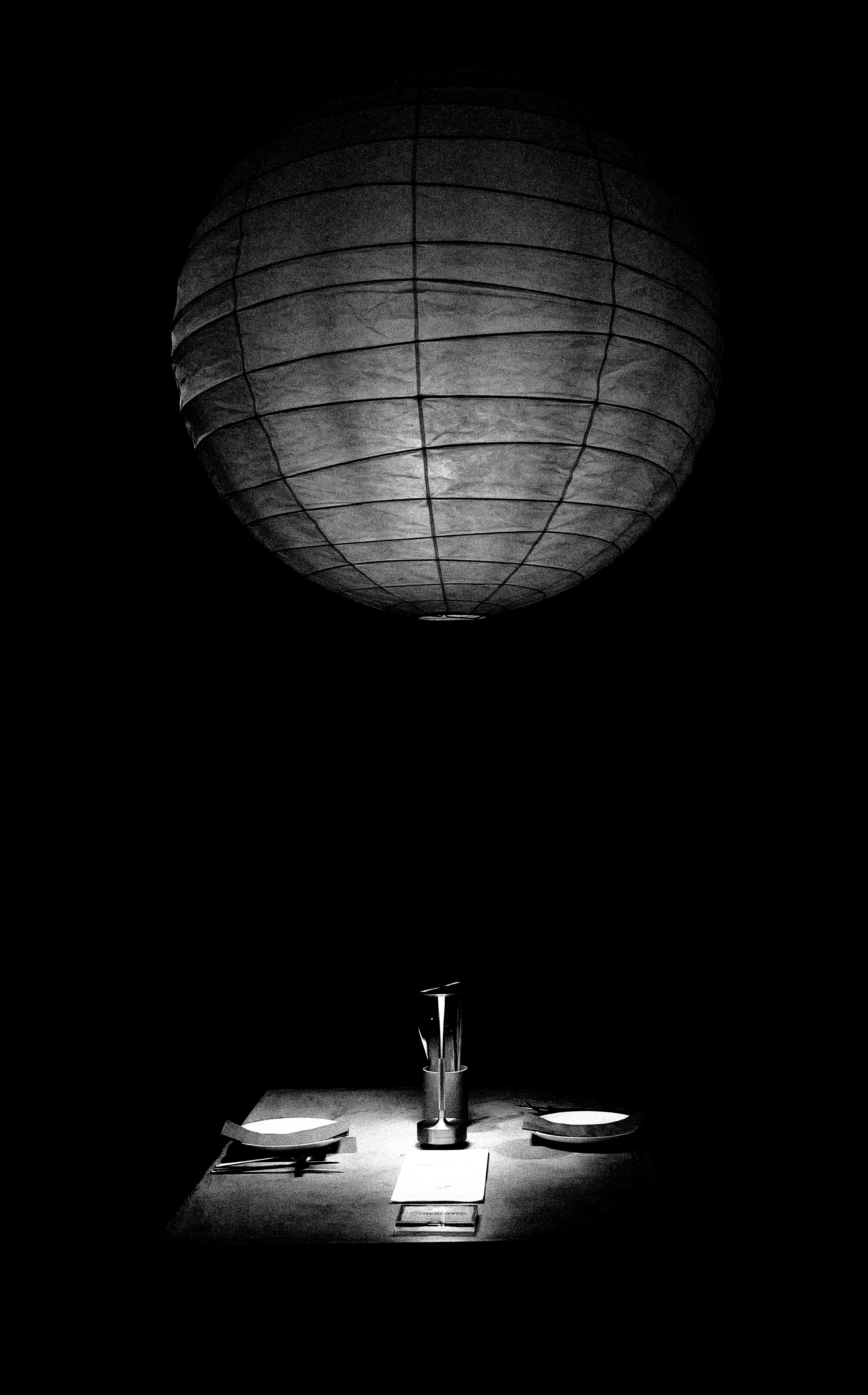 A paper lantern illuminates a table setting in darkness.