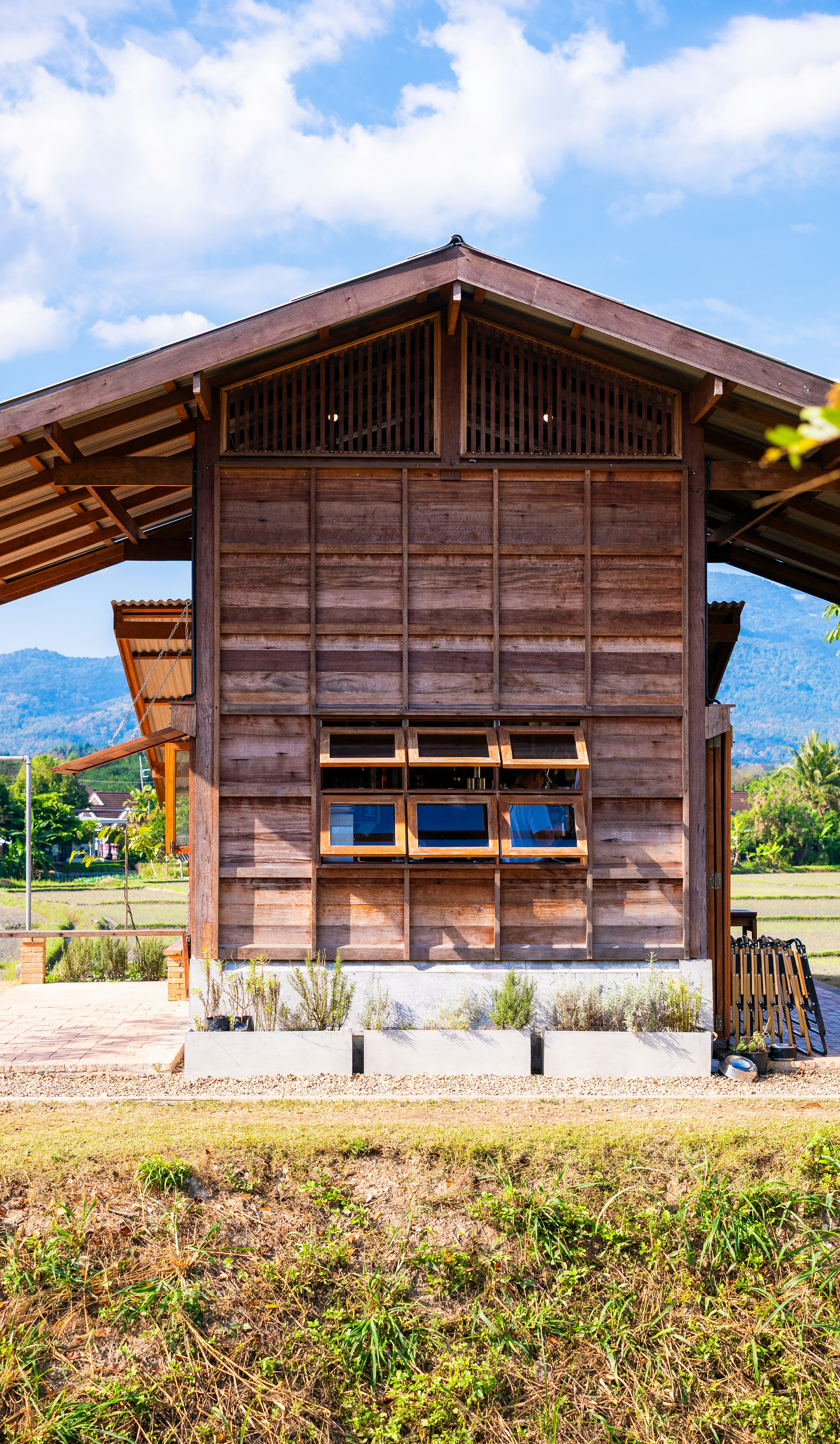 Traditional wooden building with open windows under blue sky.