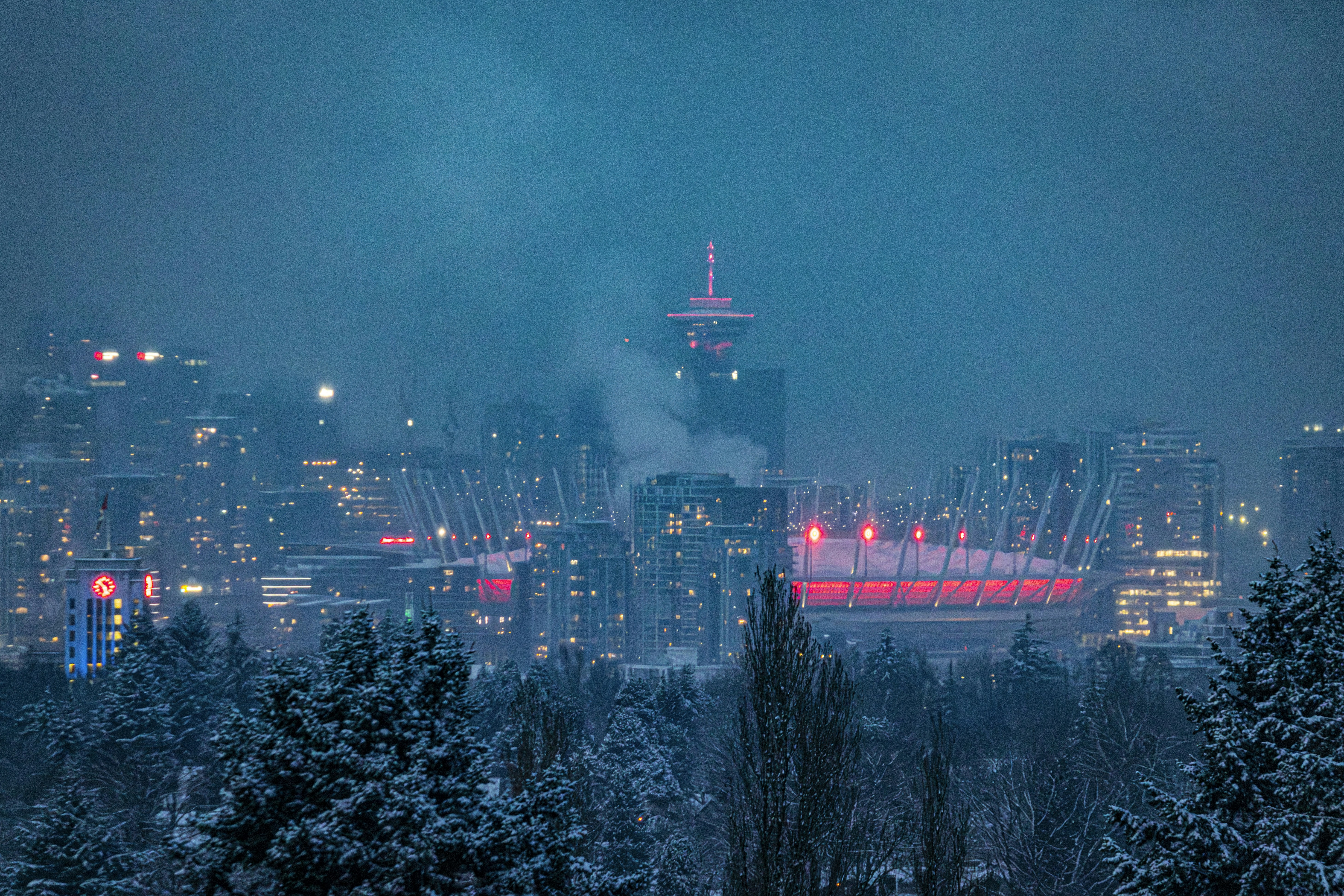 Snowy cityscape with illuminated stadium at night