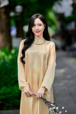 A young woman in a traditional dress holds flowers